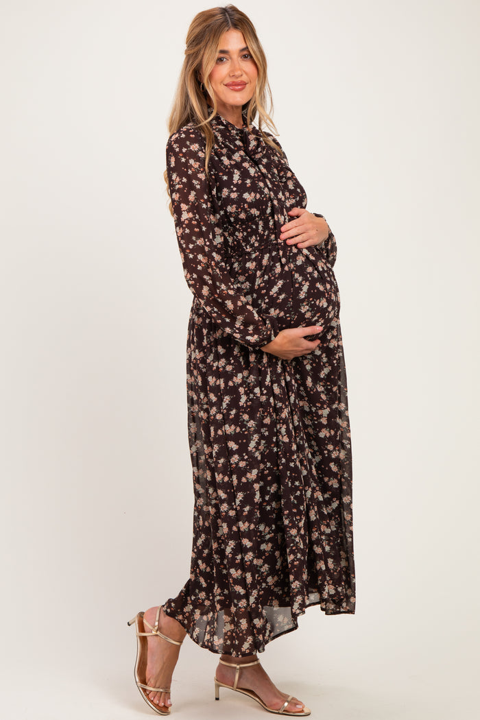 woman wearing a black floral maternity maxi dress and holding her baby bump
