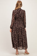 woman wearing a dark floral print maternity maxi dress with long sleeves and a cinched waist, seen from the back