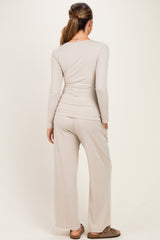 woman wearing a light beige long sleeve top and matching wide-leg pants, showing back view, styled for maternity wear