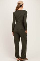 woman wearing a dark green long sleeve maternity top and matching pants, viewed from the back
