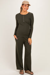 woman wearing a dark green long sleeve maternity top and matching pants, showcasing her baby bump