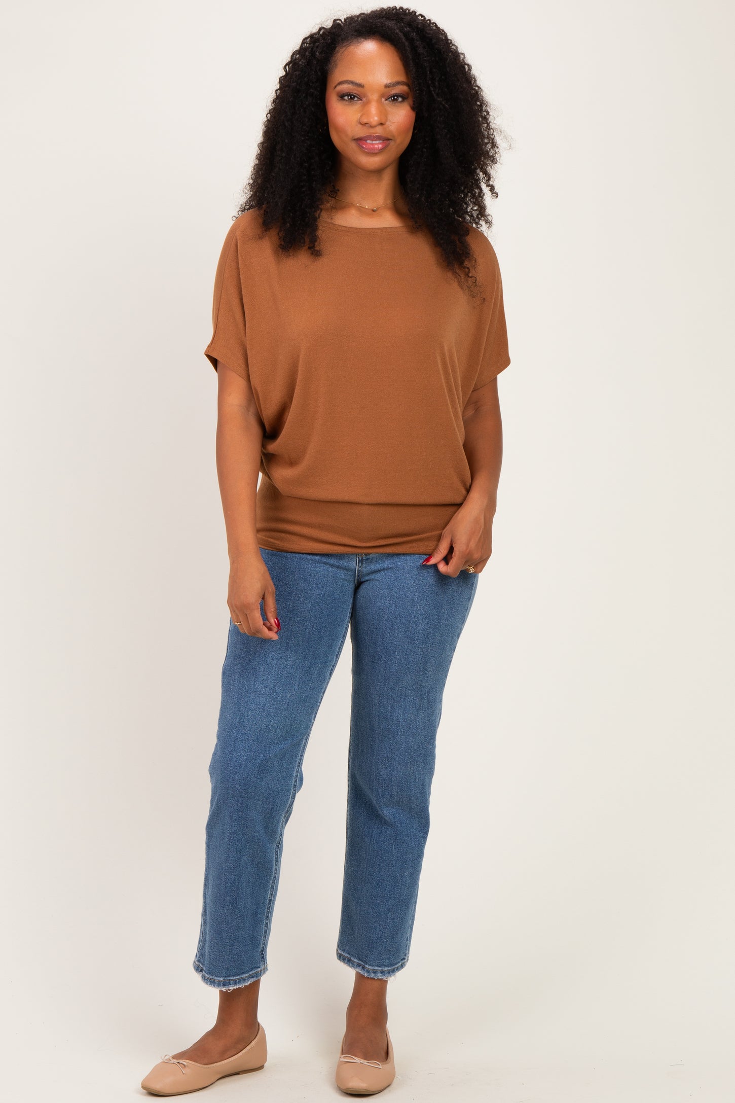 woman wearing a brown short sleeve top with a relaxed fit and blue high-waisted jeans