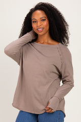 woman wearing a taupe long sleeve top with side detailing and relaxed fit, posing with one hand on her head