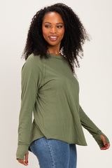woman wearing an olive green long sleeve top with side slits and thumbholes, paired with blue jeans