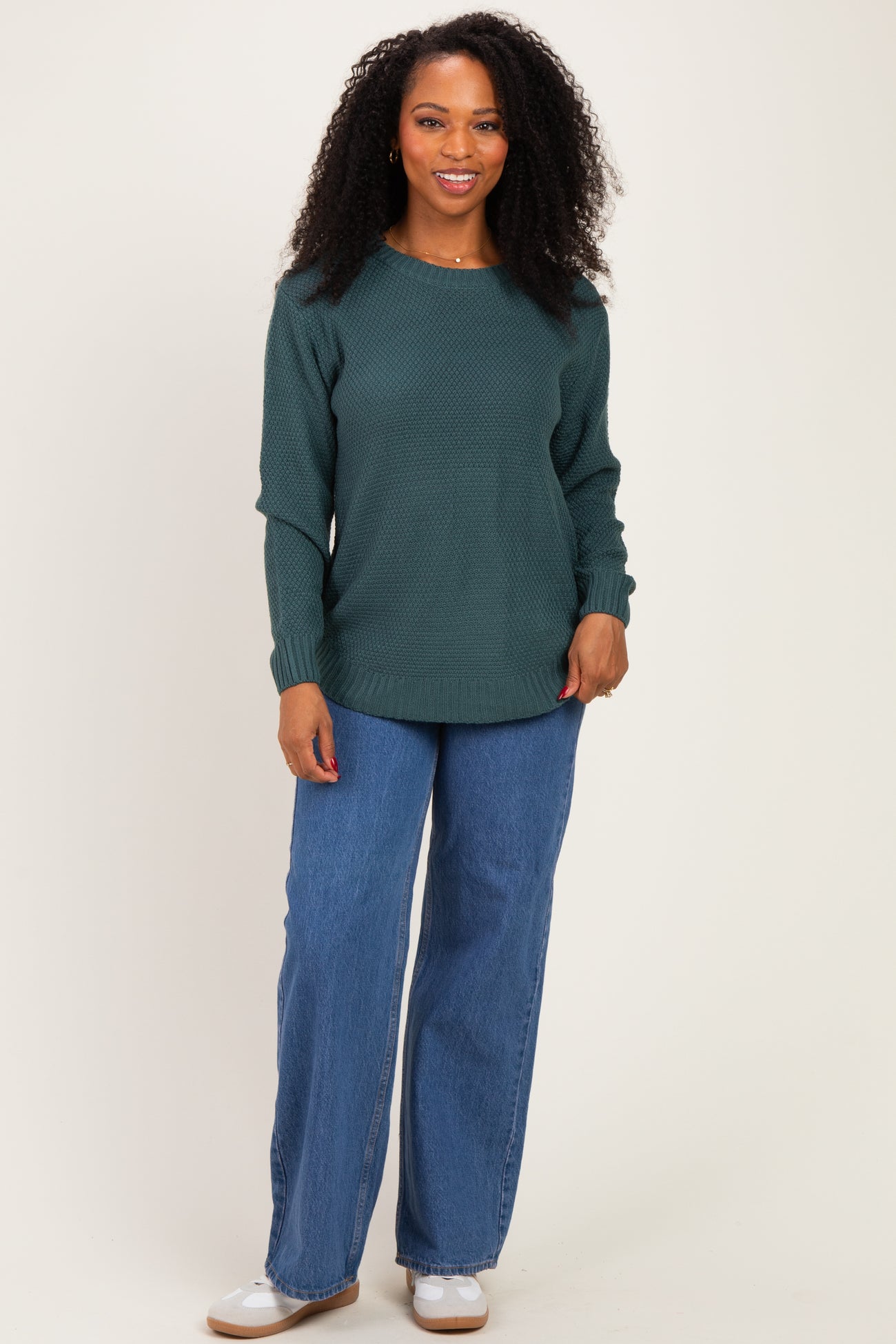 woman wearing a dark green textured long sleeve sweater and wide leg denim jeans