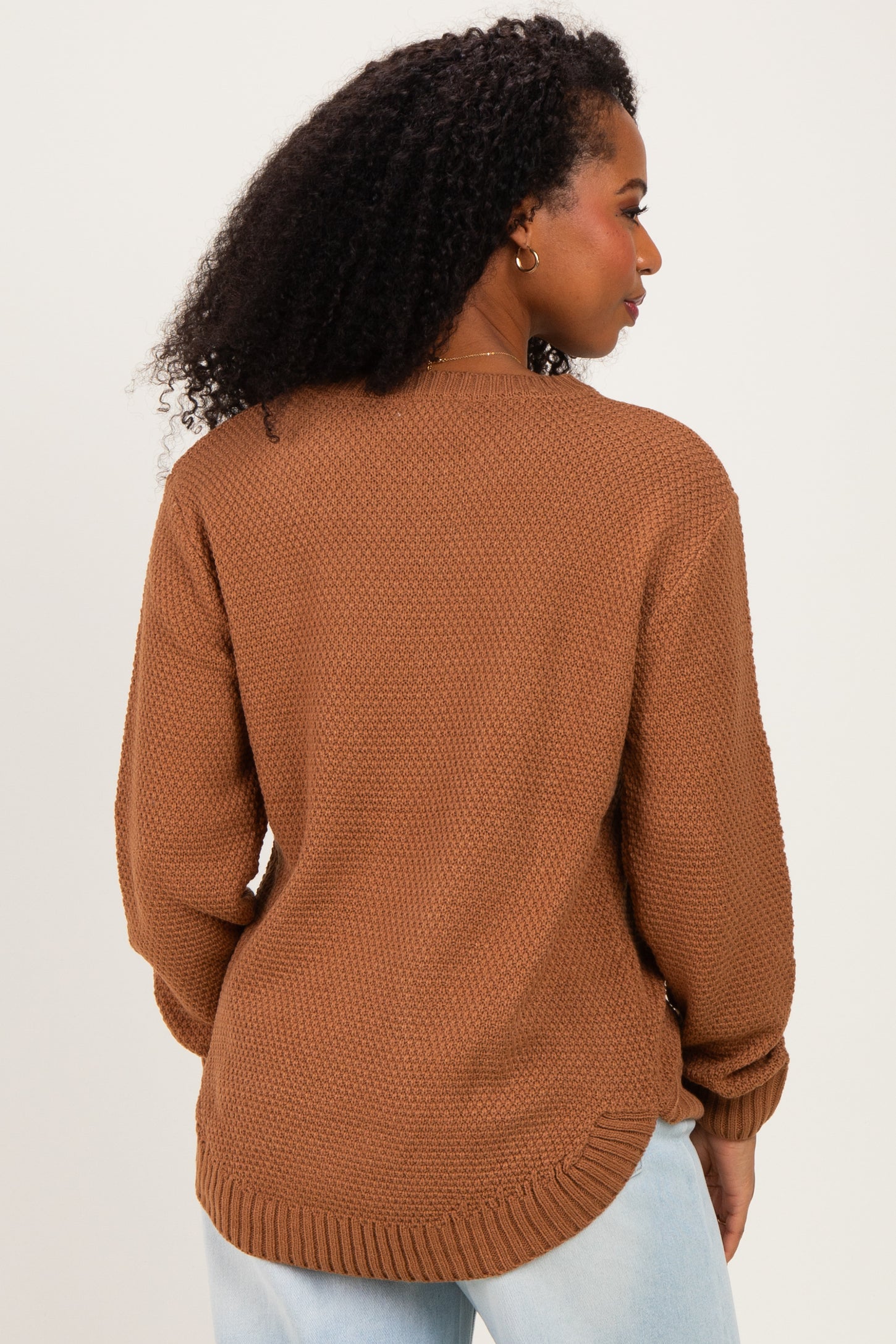 woman wearing a brown textured knit sweater with a loose fit and dropped shoulders, viewed from the back