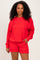 woman wearing a bright red oversized sweatshirt and matching shorts, smiling at the camera
