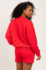 woman wearing a red oversized sweatshirt and matching shorts, showing the back view with curls styled hair