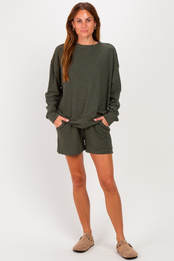woman wearing an olive green long sleeve top and matching shorts, styled casually with pockets