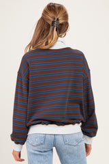 woman wearing a brown and blue striped maternity sweatshirt with a loose fit, showing a baby bump in light blue jeans
