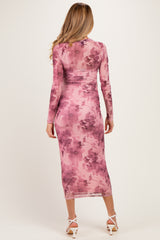 woman wearing a pink floral maternity dress with long sleeves and a fitted silhouette, showcasing a baby bump