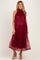 woman wearing a burgundy maternity dress with floral embroidery and a flowy silhouette, showcasing her baby bump