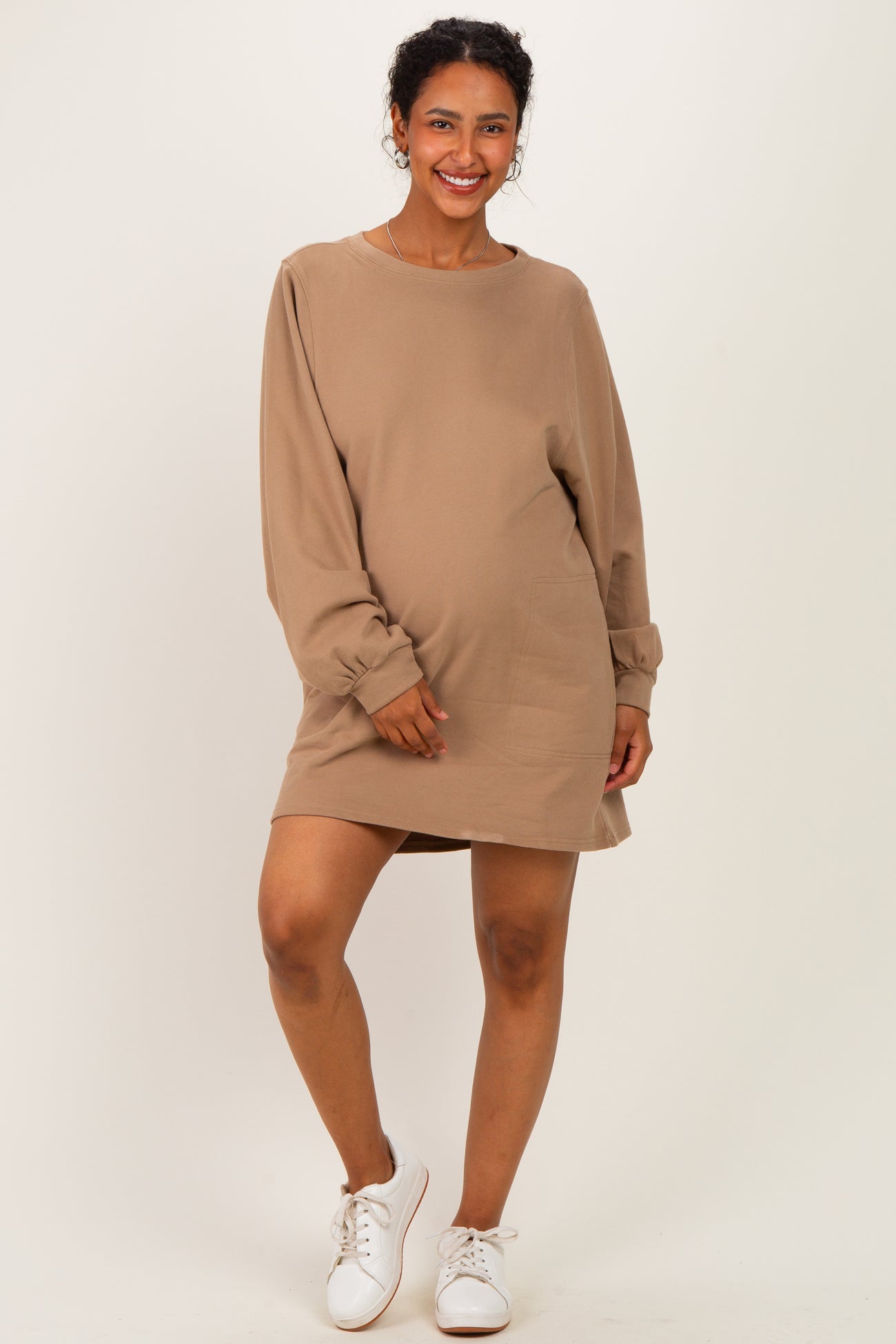 woman wearing a beige long sleeve maternity dress with a relaxed fit and pockets, showcasing her baby bump