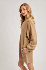 woman wearing a tan oversized hoodie dress with long sleeves and side pockets