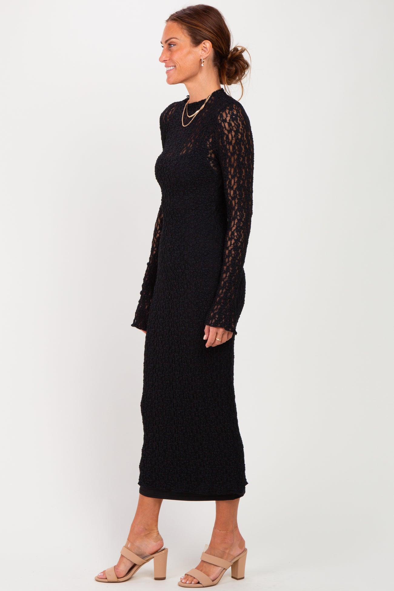 woman wearing a black long sleeve lace midi dress and beige heeled sandals