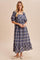 woman wearing a navy blue plaid maxi dress with puff sleeves and a ruffled hem