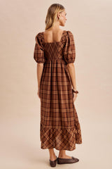 woman wearing a brown plaid long sleeve maxi dress with puffed sleeves and a smocked back detail