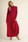 woman wearing a red knit long sleeve top with a flowing maxi skirt, posing stylishly in a studio setting