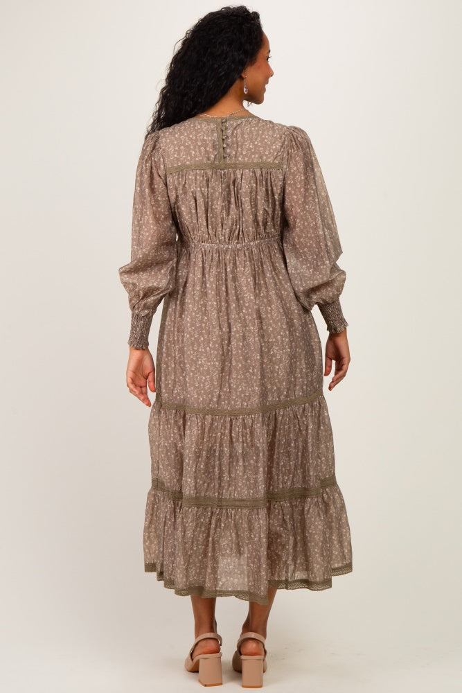 woman wearing a brown floral maternity dress with long sleeves and tiered ruffle hem, showcasing a baby bump