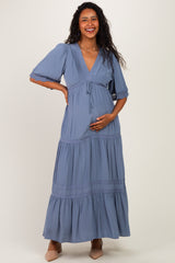 woman wearing a dusty blue maternity maxi dress with a v-neck and short sleeves, showing her baby bump