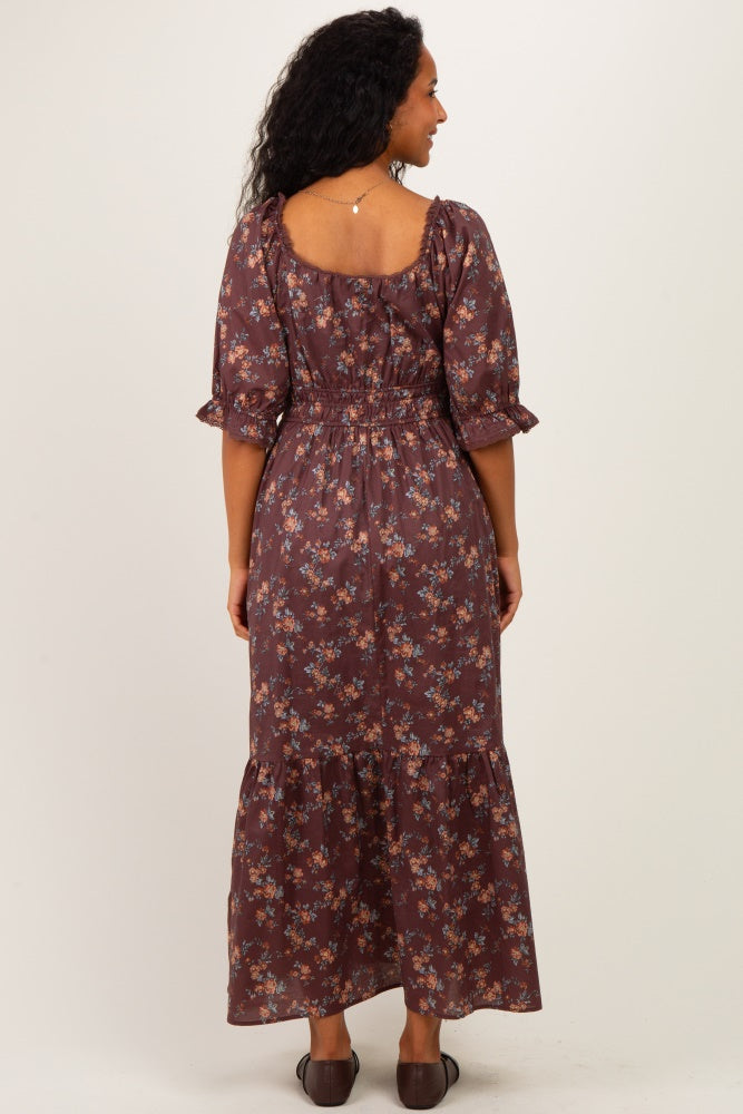 woman wearing a brown floral maternity maxi dress with puff sleeves and a tiered skirt, showcasing her baby bump from the back