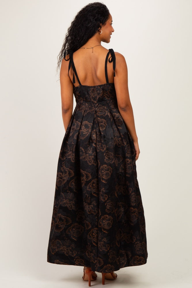 woman wearing a black maternity maxi dress with brown floral pattern and tie straps, showing the back view and no baby bump visible