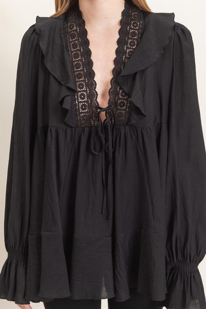 woman wearing a black ruffled blouse with lace details and long sleeves