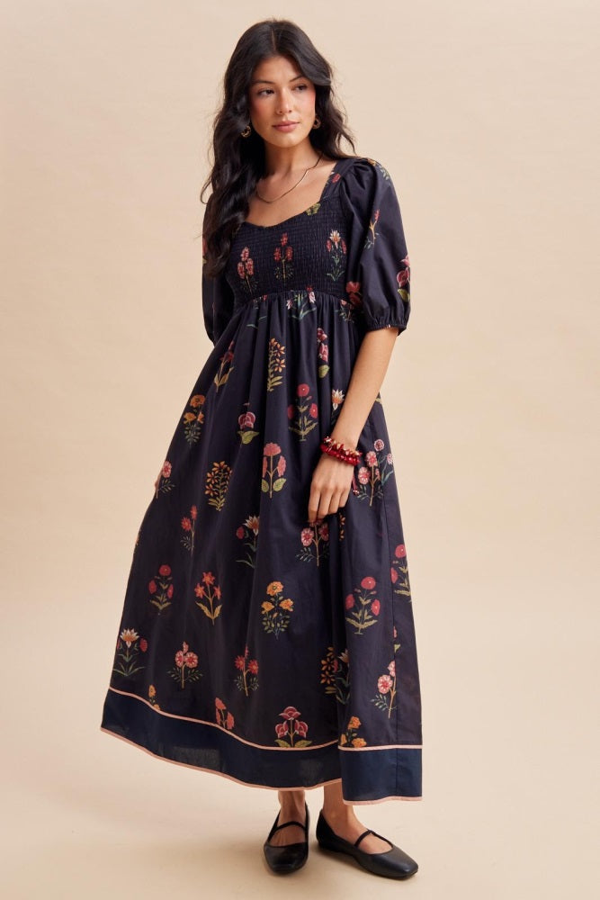 woman wearing a black floral maxi dress with puff sleeves and a smocked bodice