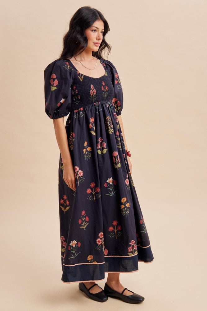 woman wearing a black floral maxi dress with puff sleeves and a smocked bodice