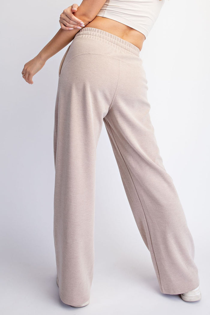 woman wearing beige wide-leg lounge pants, showing the back view with elastic waistband and relaxed fit