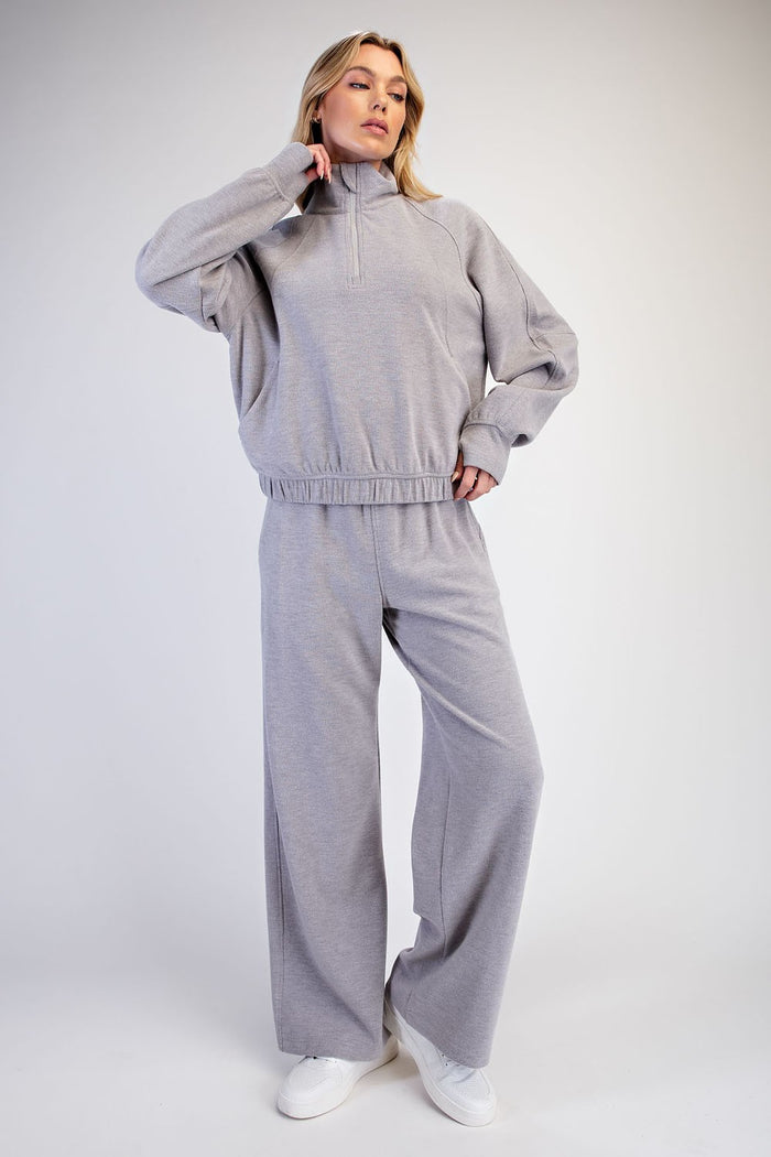 woman wearing a light gray oversized quarter-zip sweatshirt and matching wide-leg sweatpants