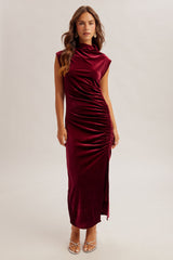 woman wearing a burgundy velvet sleeveless midi dress with side ruching and a high neckline