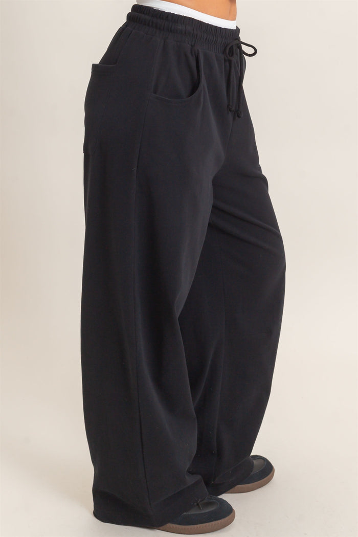 woman wearing black wide-leg sweatpants with side pockets and an adjustable drawstring waistband