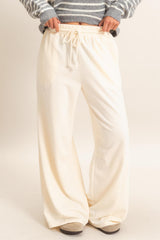 woman wearing cream wide-leg lounge pants with an elastic waistband and drawstring detail