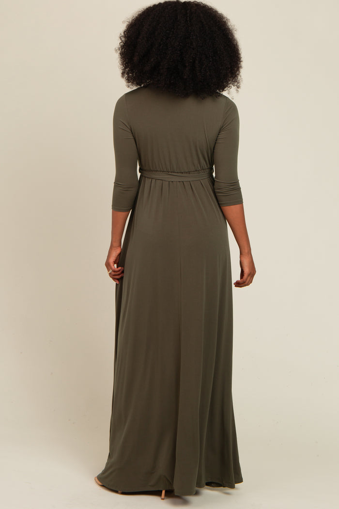 woman wearing a long olive green maxi dress with three-quarter sleeves and a cinched waist, viewed from the back