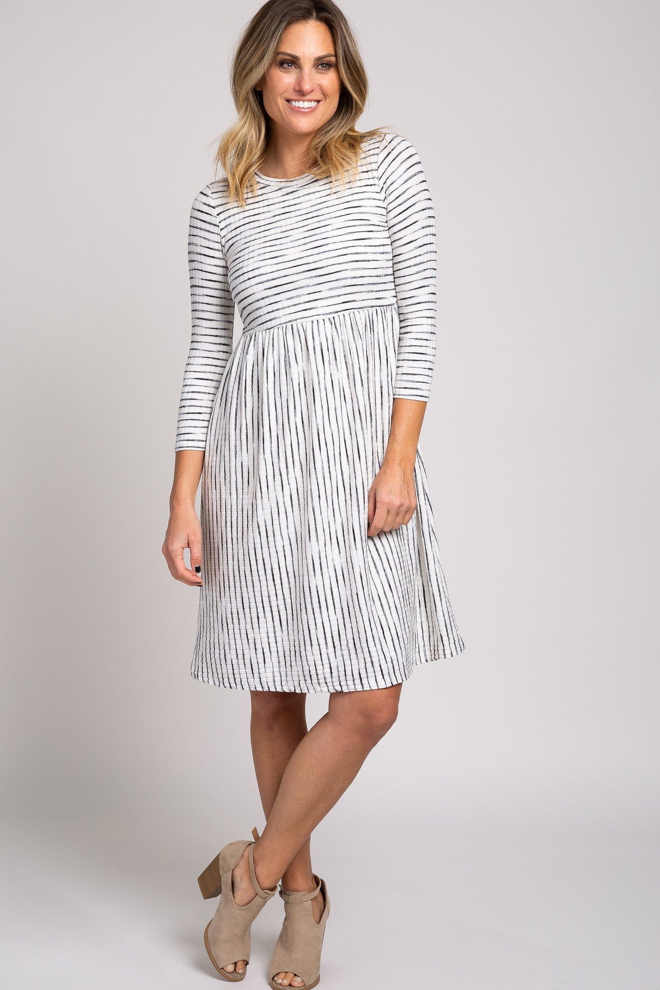 woman wearing a white and black striped long sleeve babydoll dress with tan peep toe booties