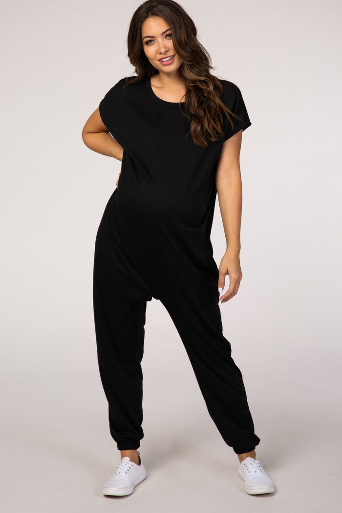 woman wearing a black maternity jumpsuit with short sleeves and a relaxed fit, showing her baby bump