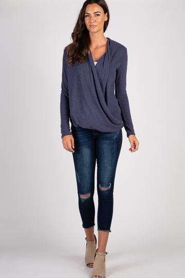woman wearing a purple long sleeve draped front top and distressed blue skinny jeans