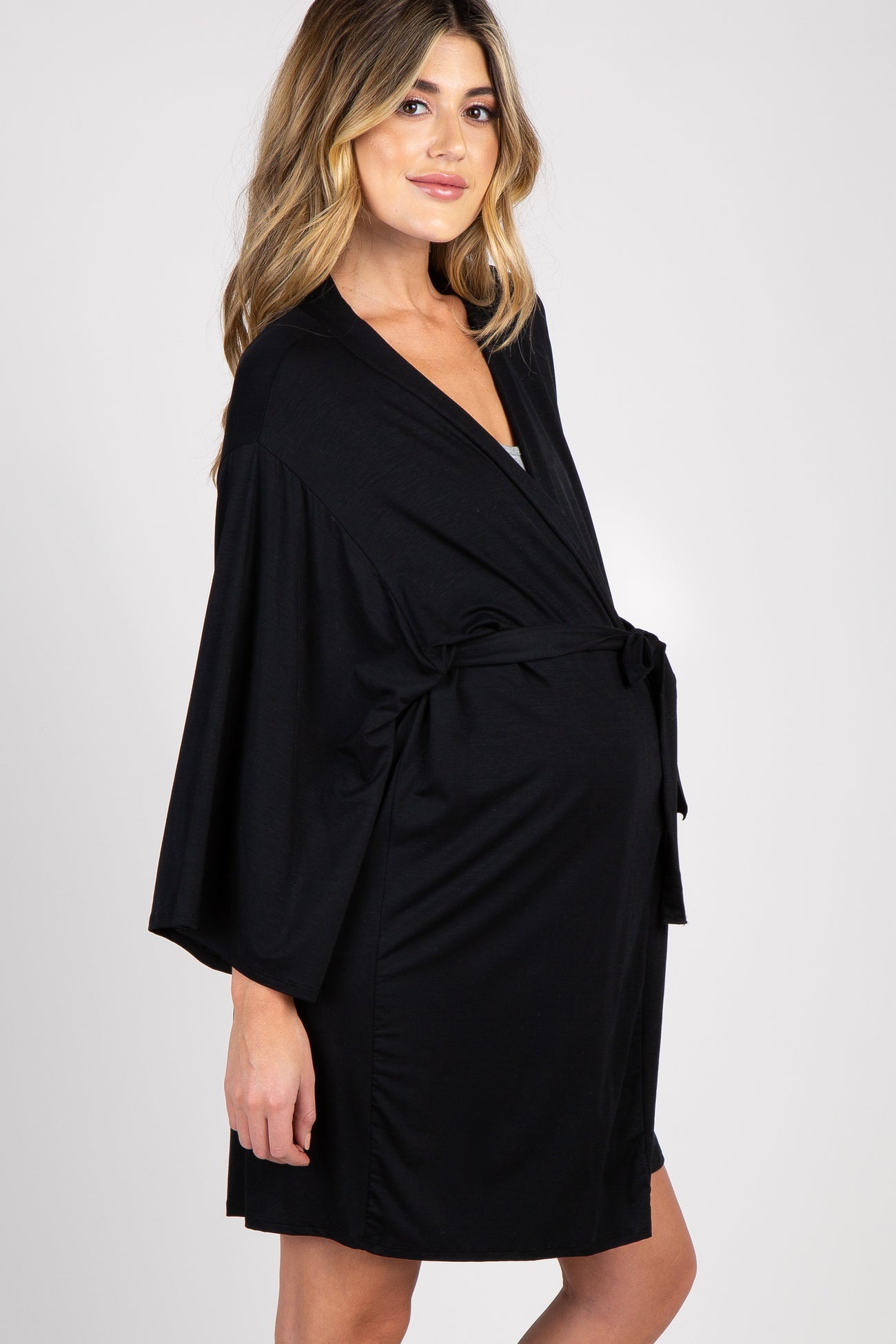 woman wearing a black maternity dress and holding her baby bump while standing in a nursery