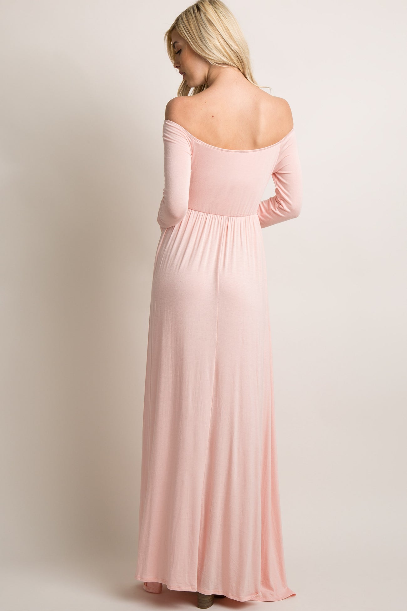 woman wearing a soft pink off-the-shoulder long sleeve maxi dress, showing the back view