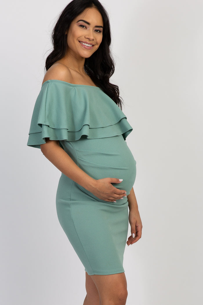 woman wearing a ribbed mint green off-shoulder maternity dress highlighting her baby bump