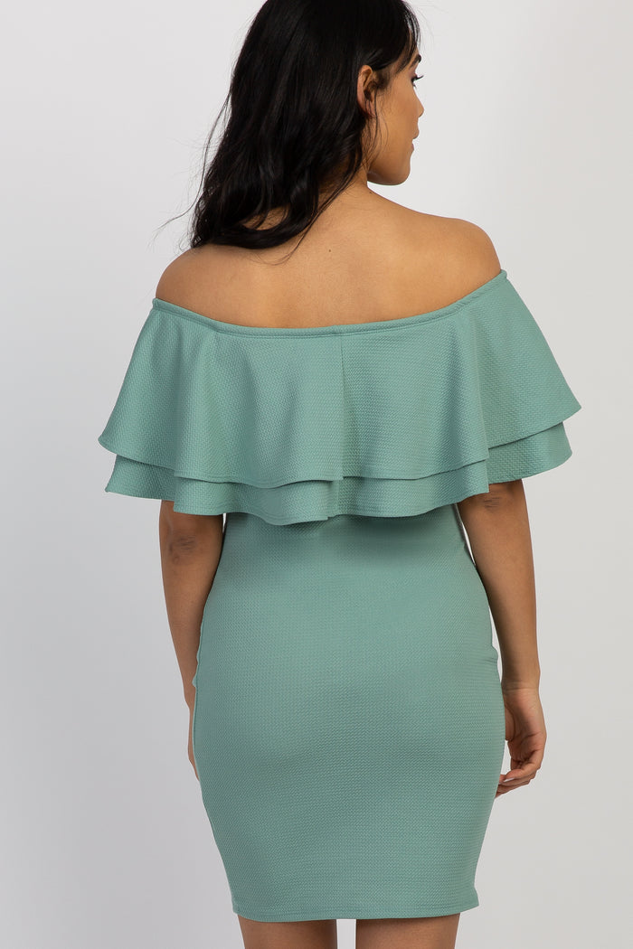 woman wearing a green off-the-shoulder maternity dress with ruffles and showing her baby bump