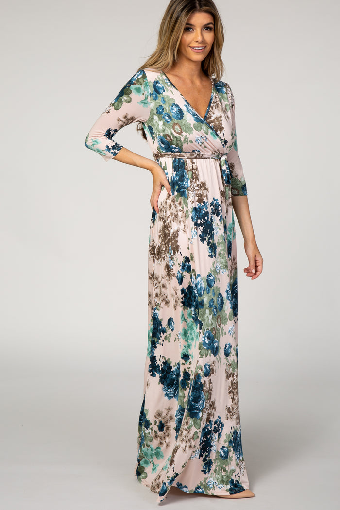 woman wearing a floral maxi dress with a wrap style and 3/4 sleeves in shades of blue and green