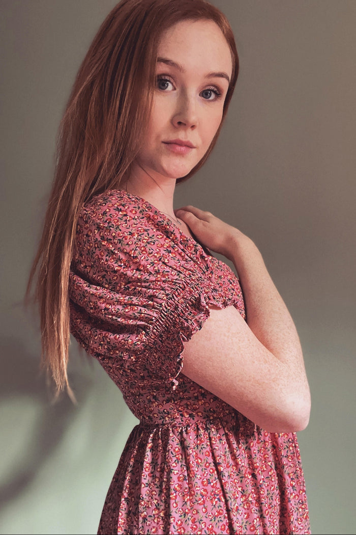 woman wearing a pink floral short sleeve dress with ruffled sleeves and a smocked bodice