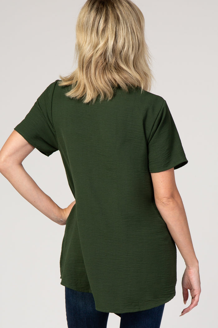 back view of a woman with blonde hair wearing a forest green short sleeve textured top and dark jeans
