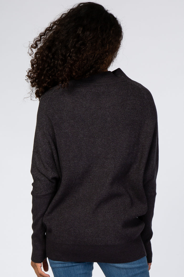 woman wearing a dark gray oversized sweater with a relaxed fit and open back, viewed from the back