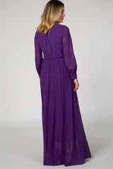 woman wearing a long sheer purple maxi dress with long sleeves and cinched waist, shown from the back