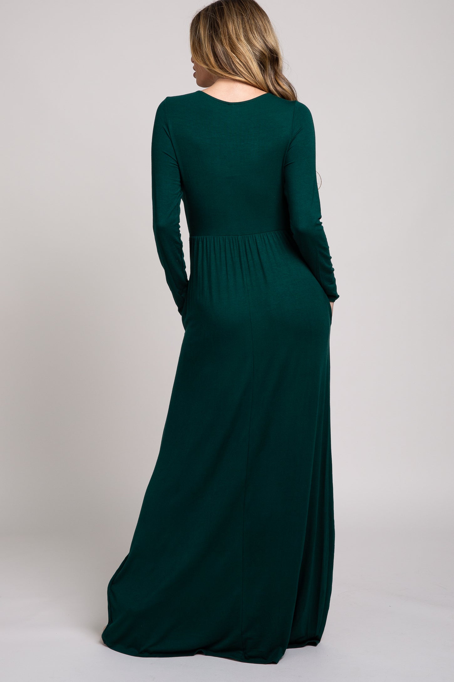 woman wearing a long sleeve dark green maxi dress viewed from the back