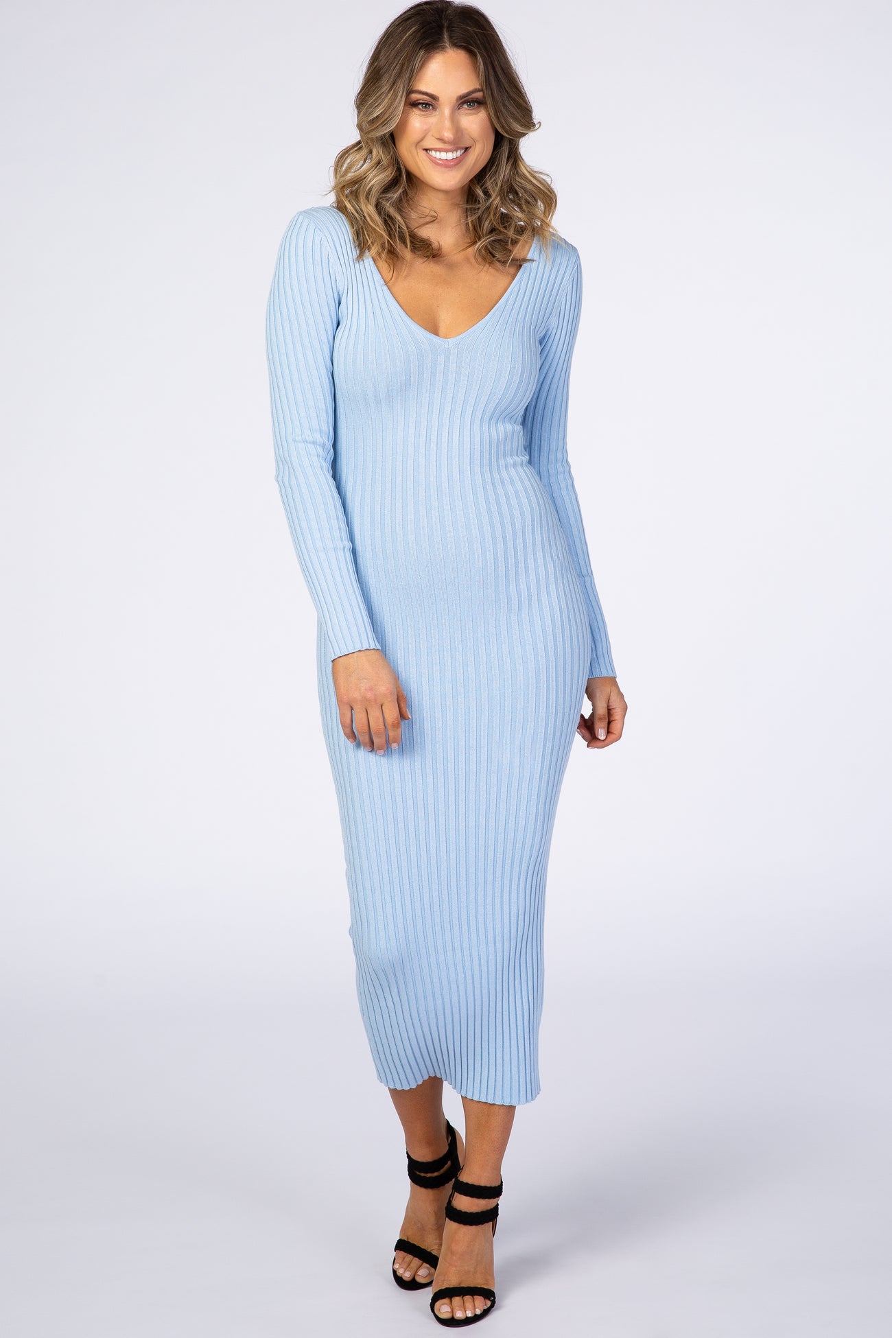 woman wearing a light blue ribbed long sleeve bodycon dress with a deep v-neckline and strappy heels