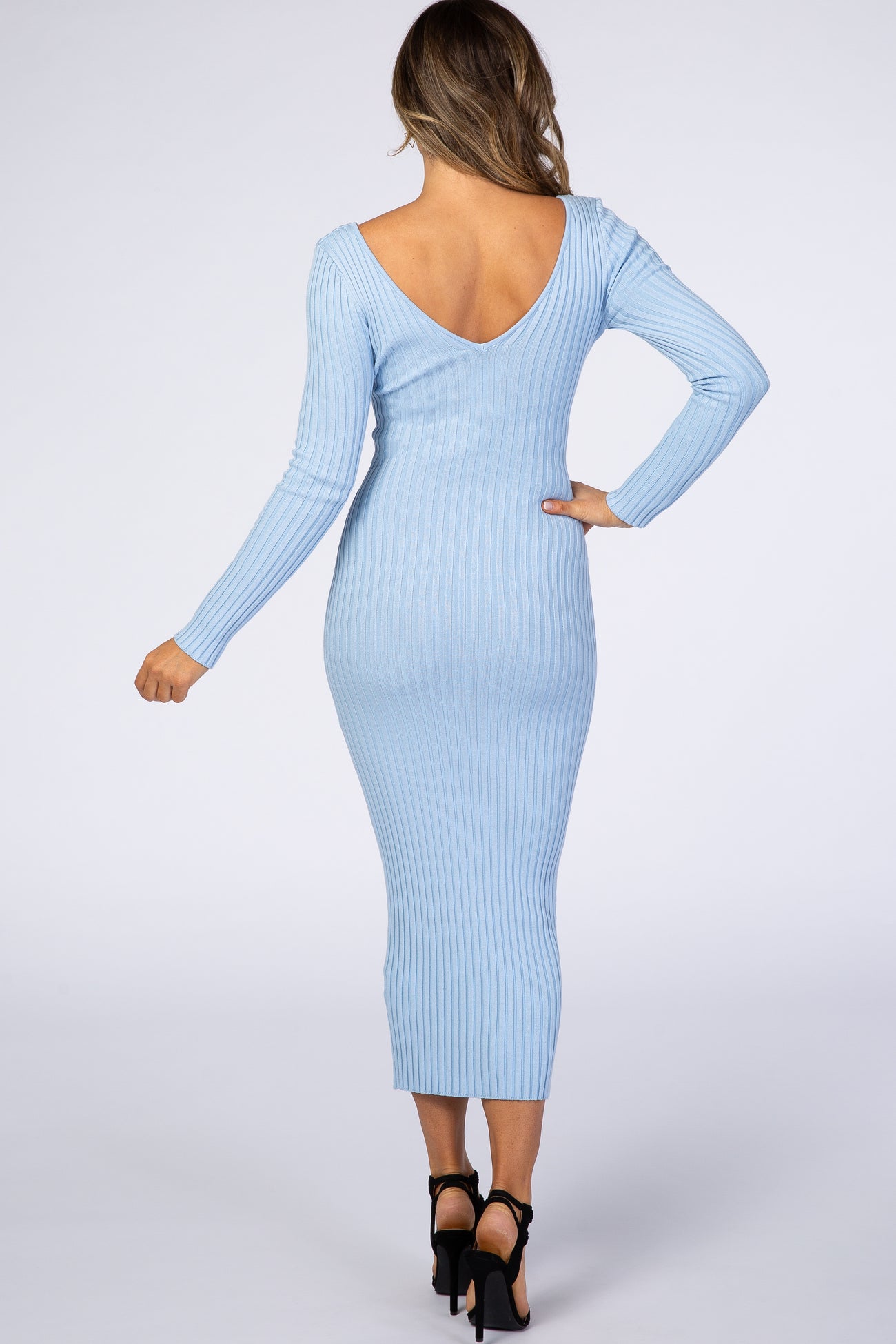 woman wearing a light blue ribbed midi dress with a deep v-back and long sleeves, showing a fitted silhouette